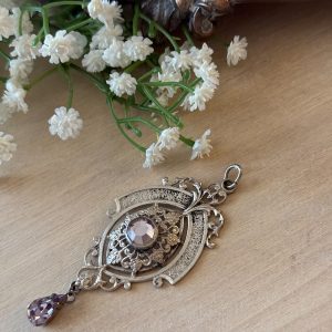 Antique Austro-Hungarian style silver pendant featuring a central oval frame, detailed engraving, and faceted amethyst-colored glass drops.