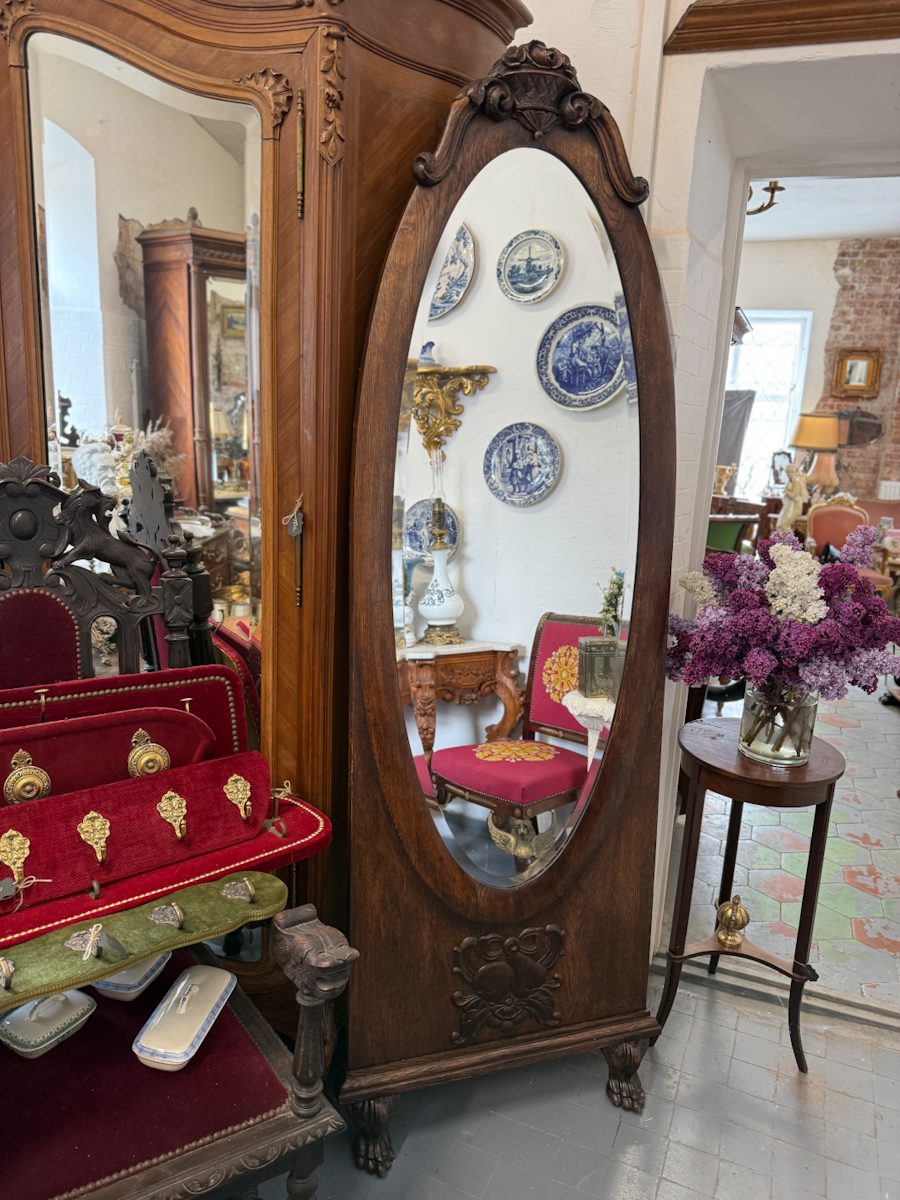 Large antique French style oak cheval floor mirror with a thick bevelled glass, ornate rose basket cresting, and carved lion paw feet.
