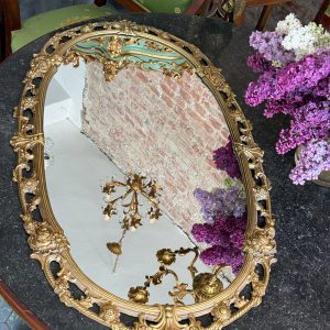 Antique French Louis XV style gilt bronze oval wall mirror featuring ornate scrolling openwork, acanta leaves, and floral medallions.