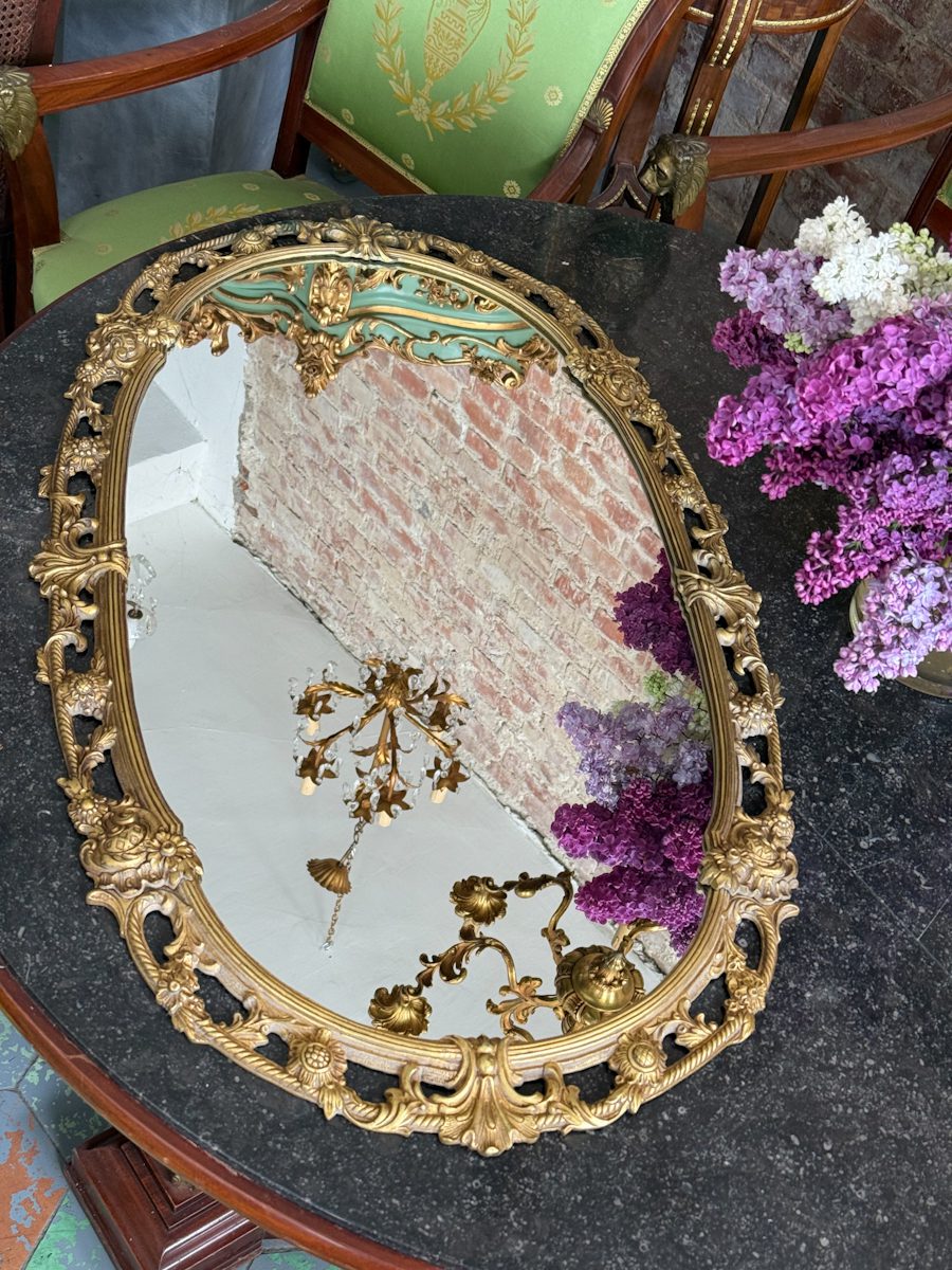 Antique French Louis XV style gilt bronze oval wall mirror featuring ornate scrolling openwork, acanta leaves, and floral medallions.